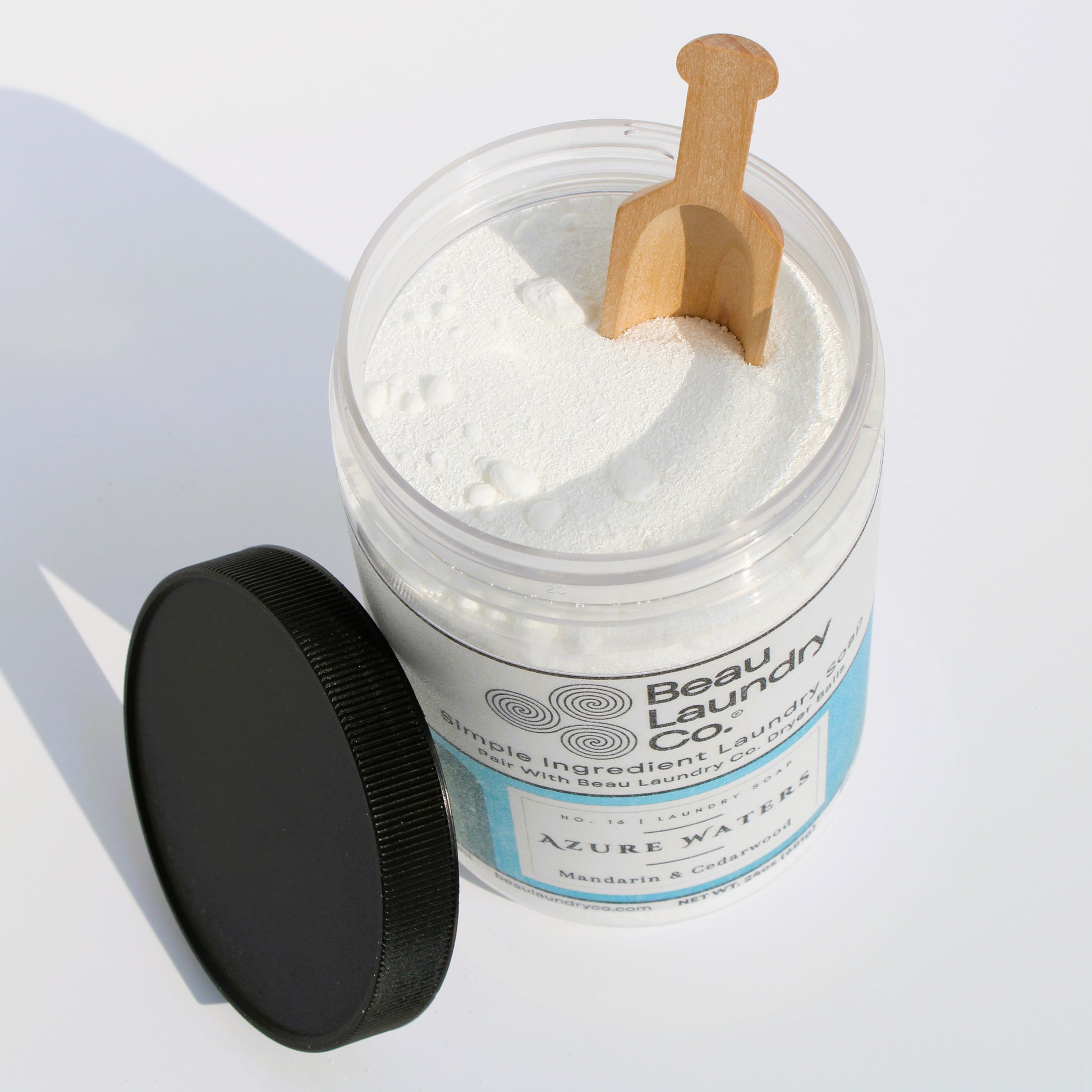 Jar of Beau Laundry Co. laundry detergent with a wooden scoop on a light background